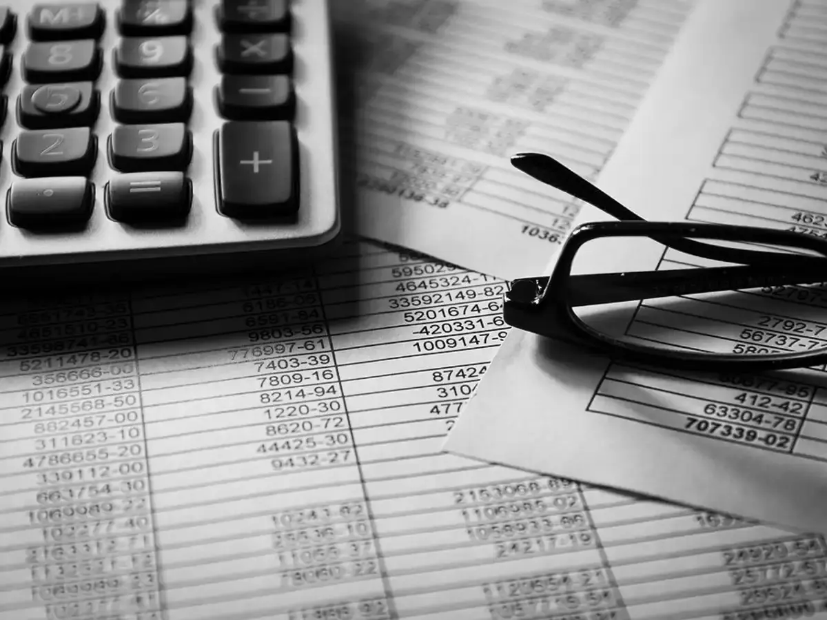 Calculator and reading glasses on printed financial schedules