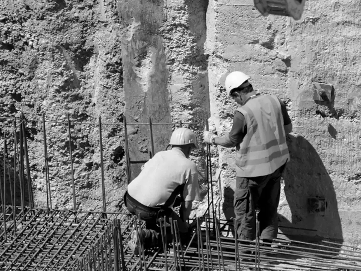 Two builders in hard hats and high-visibility vests working on site