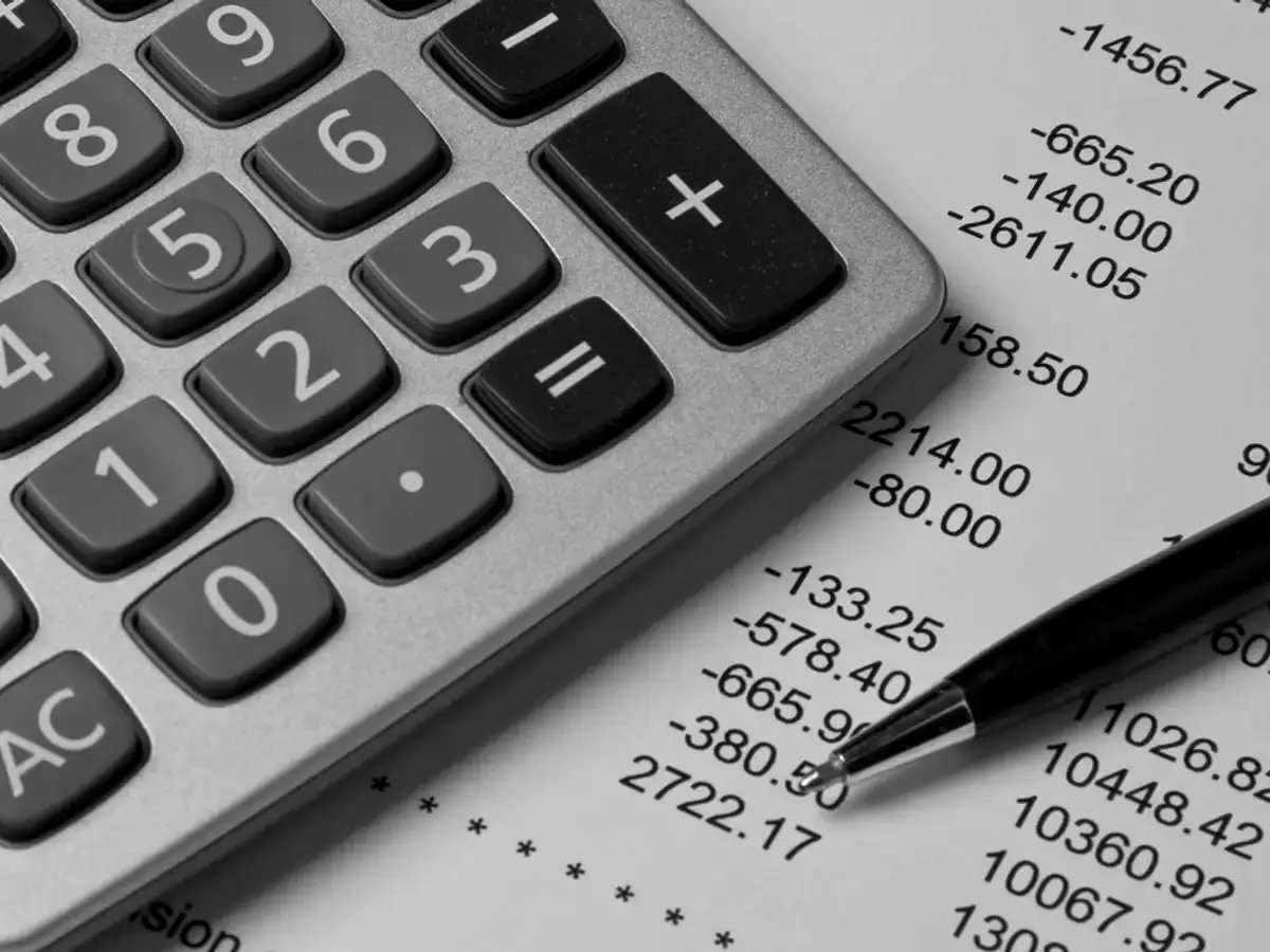Calculator and pen resting on a printed column of figures