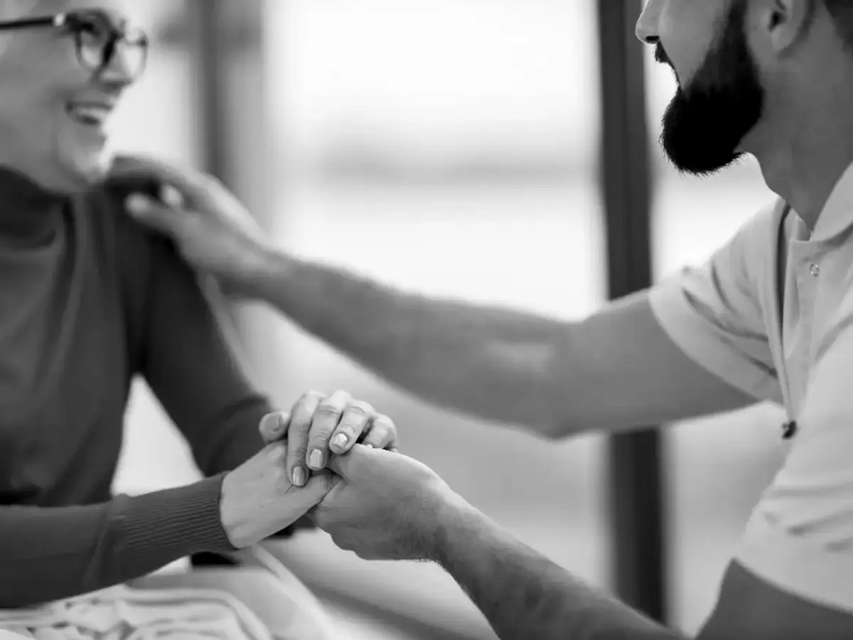 Carer holding the hands of an older woman