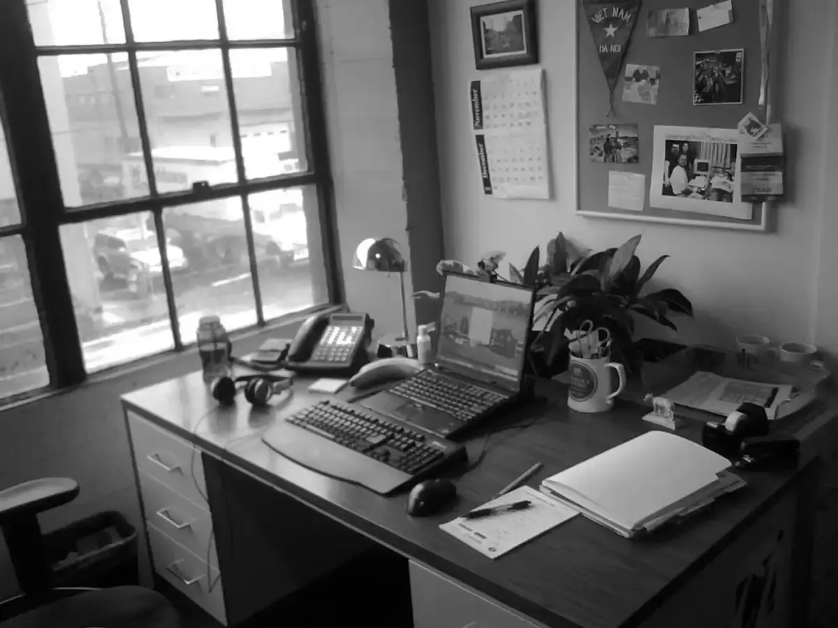 Office desk by a window with a telephone, keyboard and notepad