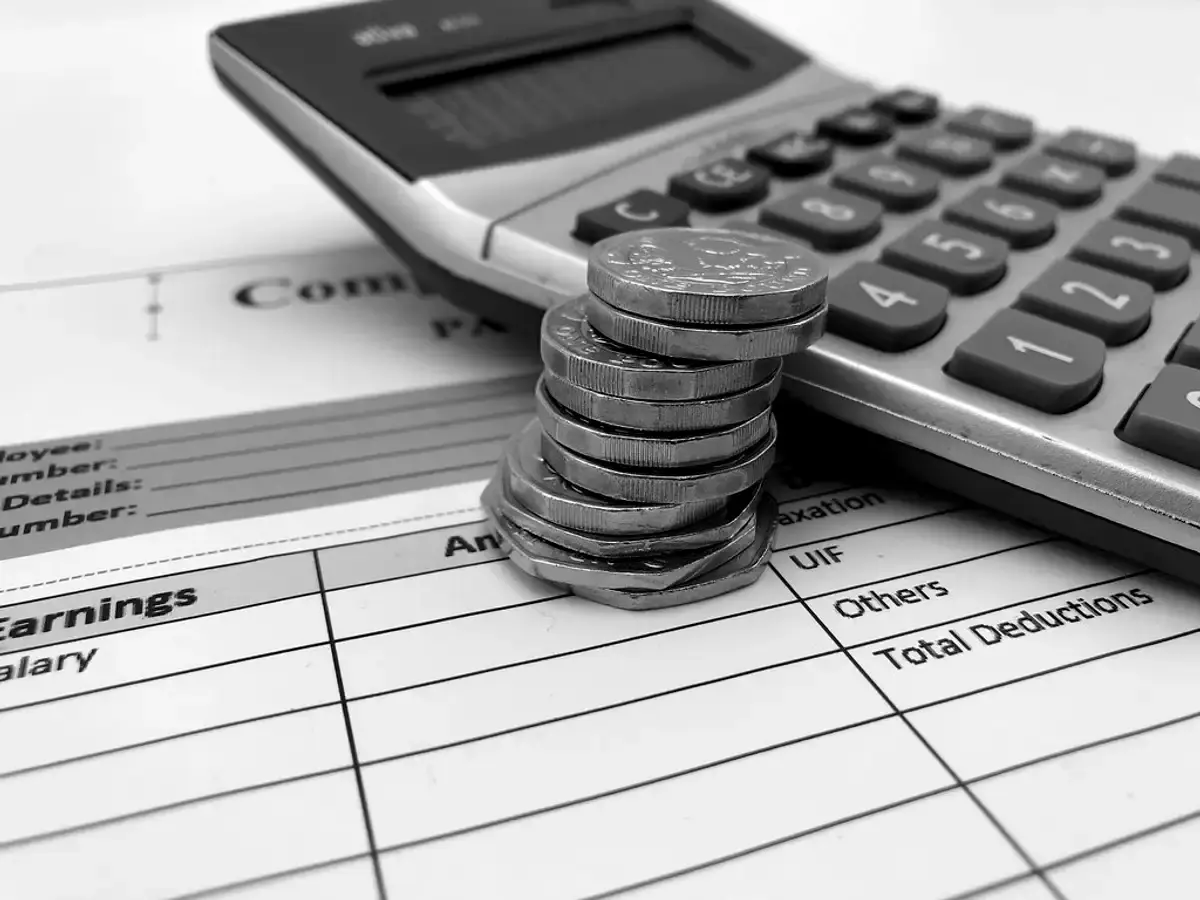 Wage slip showing earnings and deductions, with a calculator and a stack of coins